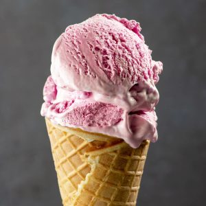 cherry ice cream in waffle cone on dark grey background